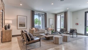 A spacious living room with a sofa, chairs, a coffee table, and a fireplace. - Landing | Stunning 2BD, Gym, Courtyard (San Antonio)