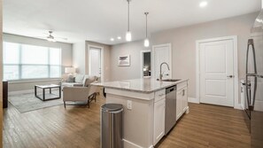 A modern kitchen with a central island, white cabinetry, and stainless steel appliances. - Landing | Beautiful 2BD, Courtyard, Gym (San Antonio)