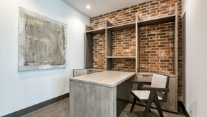 A conference room with a brick wall, a large abstract painting, and a modern table and chairs. - Landing | Stunning 2BD, Gym, Courtyard (San Antonio)