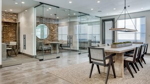 Een modern interieur met een keuken met glazen wanden, een eethoek met een grote tafel en stoelen, en een accentmuur van baksteen.