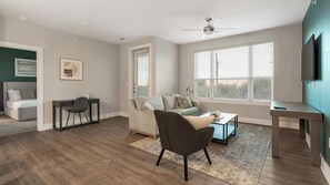 Een moderne woonkamer met een bank, fauteuil, salontafel en een tv op een dressoir.