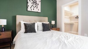 A hotel room with a bed, two bedside tables, a nightstand, a wall art piece, and a walk-in closet. - Landing | Stunning 2BD, Gym, Courtyard (San Antonio)