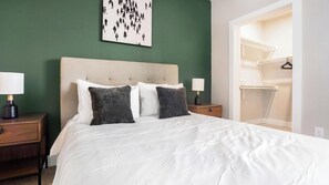 Ein Hotelzimmer mit einem Bett, zwei Nachttischen, einem Schrank und einem Kunstwerk an der Wand.