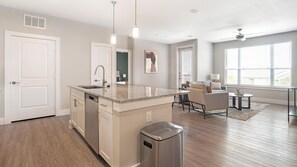 A modern kitchen with a central island, stainless steel appliances, and pendant lighting. - Landing | Incredible 2BD, Courtyard, Gym (San Antonio)