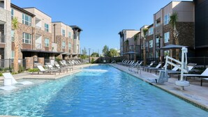 A swimming pool with lounge chairs and a brick building with multiple windows. - Landing | Stunning 2BD, Gym, Courtyard (San Antonio)
