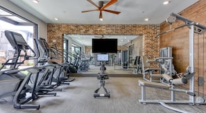 Ein Fitnessraum mit Laufbändern, Kraftgeräten und einem Deckenventilator.