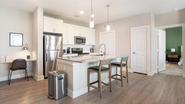 A modern kitchen with stainless steel appliances, a bar area, and a trash bin. - Landing | Stunning 2BD, Gym, Courtyard (San Antonio)