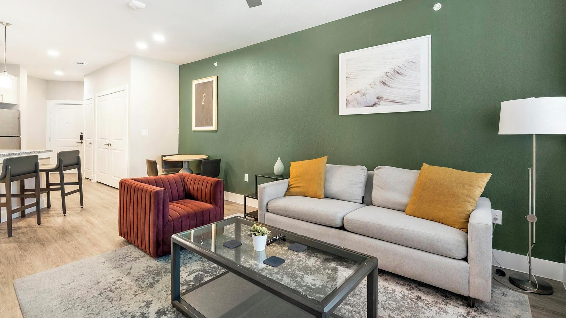 Ein modernes Wohnzimmer mit einer Couch, einem Glastisch und einem Essbereich mit Stühlen.