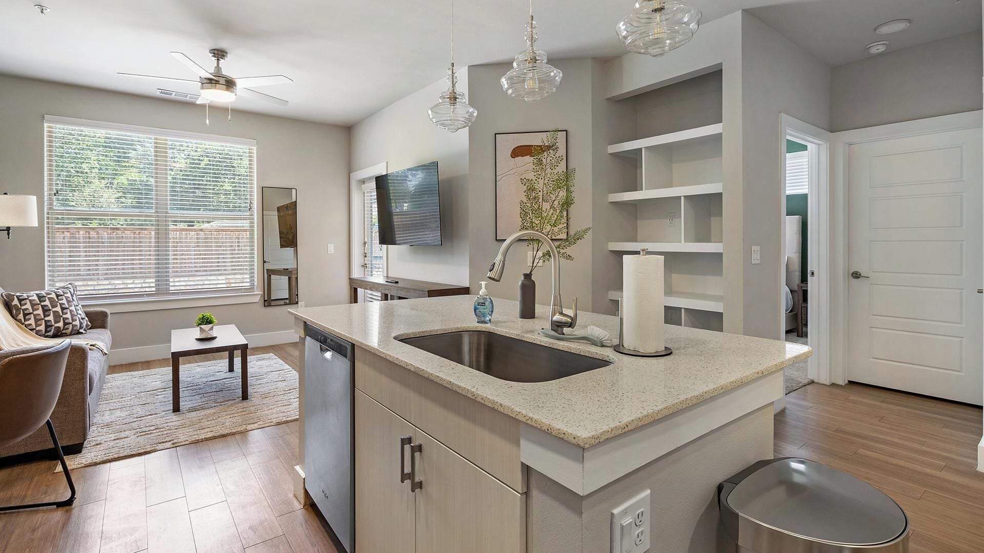 A modern kitchen with a central island, stainless steel appliances, and pendant lighting.