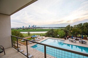 A rooftop pool with lounge chairs, a barbecue area, and a view of a city skyline. - Landing | Stunning 1BD, Clubhouse, Gym (Fort Worth)