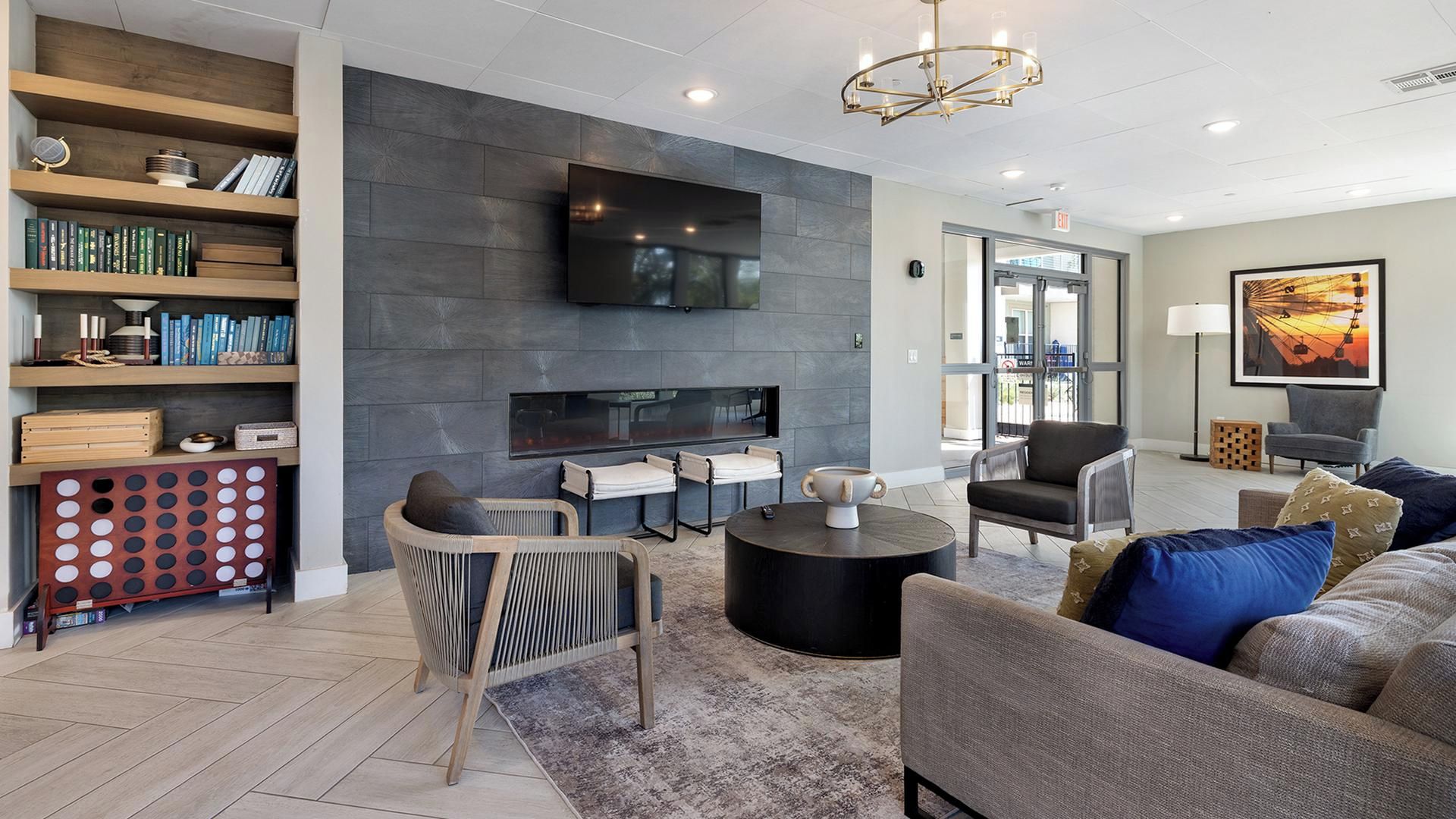 A modern living room with a flat-screen TV, comfortable seating, a fireplace, and a bookshelf.