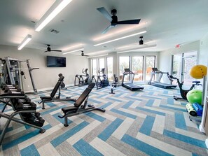 A gym with various exercise equipment, large windows, and a patterned floor. - Landing | Chic 2BD, Clubhouse, Gym (Fort Worth)