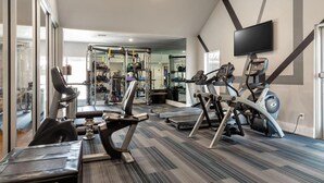 A gym with cardio machines, weightlifting equipment, and a mirrored wall. - Landing | Chic 2BD, Gym, Courtyard (Allen)