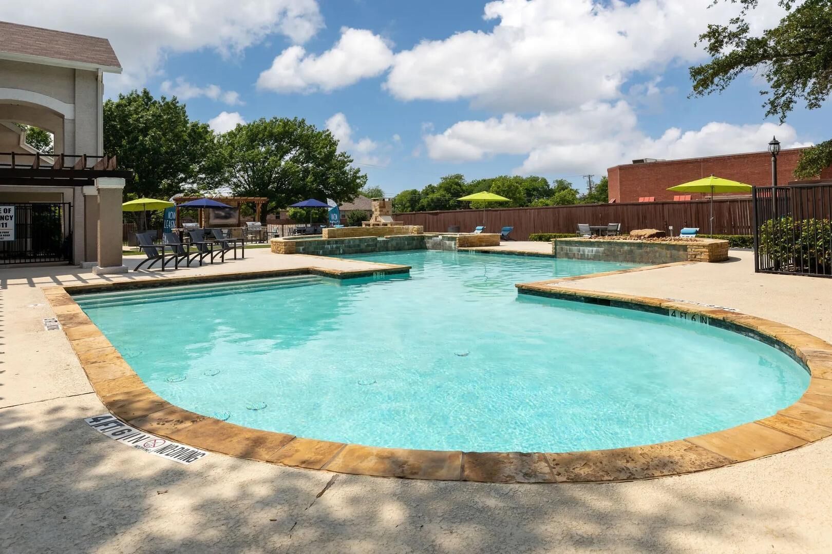 Une piscine à bords incurvés, entourée de chaises longues et de parasols.