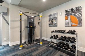 A gym with a cable machine, dumbbells, and artwork on the walls. - Landing | Stylish 1BD, Courtyard, Gym (Allen)