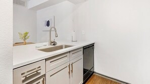 A kitchen with a stainless steel sink, a dishwasher, and a white countertop. - Landing | Spectacular 1BD, Courtyard, Gym (Allen)