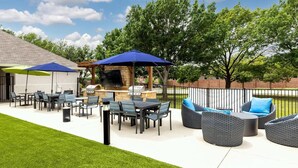 Un patio al aire libre con una parrilla, zona de estar y sombrillas.