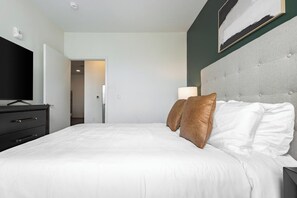 A hotel room with a bed, a television, a dresser, and a painting on the wall.