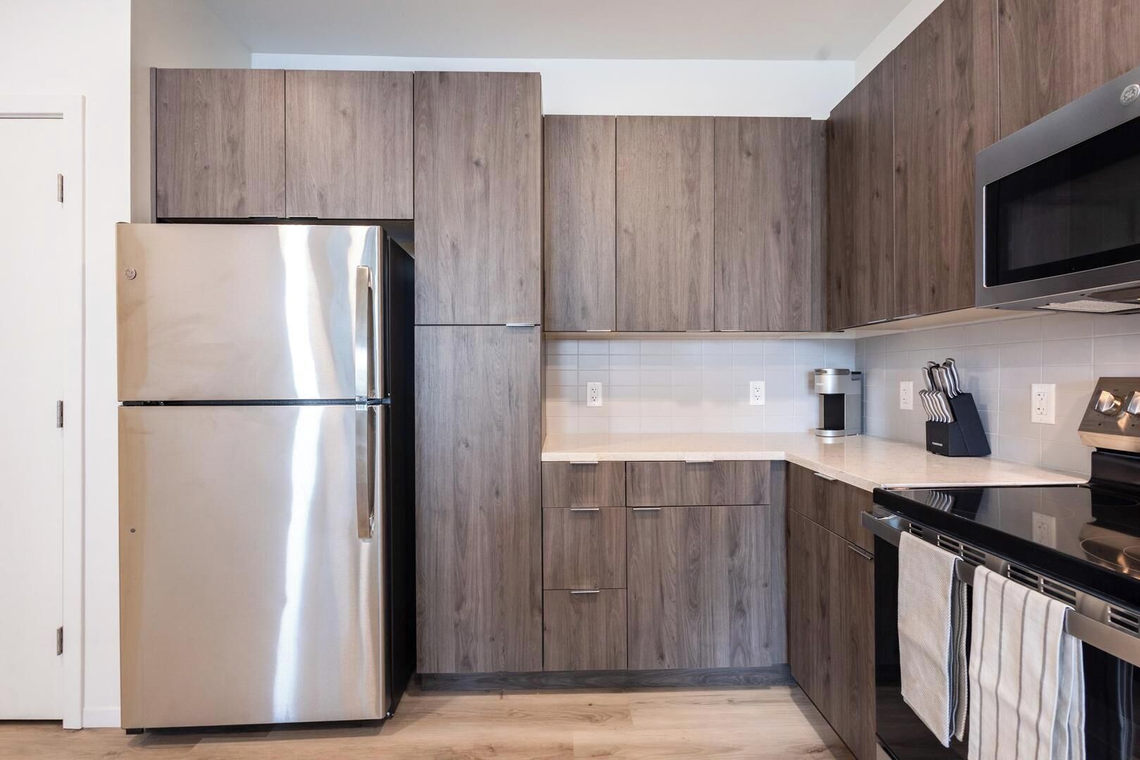 Une cuisine moderne avec des meubles en bois, des appareils en acier inoxydable et un plan de travail noir.