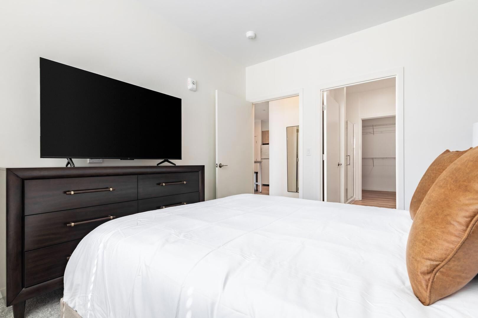 Une chambre à coucher avec un lit, une commode, un téléviseur et un placard.
