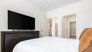 A bedroom with a bed, a dresser, a television, and a closet. - Landing | Spectacular 2BD in Steelpointe Harbor (Bridgeport)