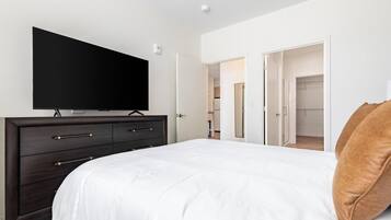 Une chambre à coucher avec un lit, une commode, un téléviseur et un placard.