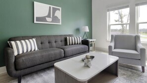 Ein Wohnzimmer mit grauem Sofa, weißem Couchtisch und grauem Sessel.