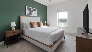 A bedroom with a bed, nightstands, a lamp, a television, and a window. - Landing | Amazing 1BD, Gym (St. Augustine)