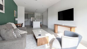 Ein stilvolles Wohnzimmer mit einer Couch, einem Couchtisch und einem an der Wand befestigten Fernseher.