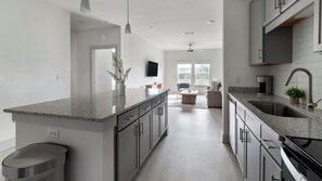 A modern kitchen with granite countertops, stainless steel appliances, and a central island. - Landing | Amazing 1BD, Gym (St. Augustine)