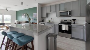 Eine moderne Küche mit grauen Schränken, einem Edelstahl-Kühlschrank, einer Mikrowelle und einem eingebauten Backofen.