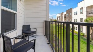 Un balcon avec deux chaises et une table, donnant sur un quartier résidentiel composé de plusieurs immeubles d’appartements.