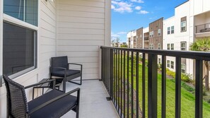 Ein Balkon mit zwei Stühlen und einem Tisch, mit Blick auf eine Wohngegend mit mehreren Mehrfamilienhäusern.