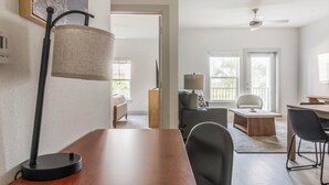 Un salon moderne avec une table à manger en bois, des chaises noires, un canapé et une lampe.
