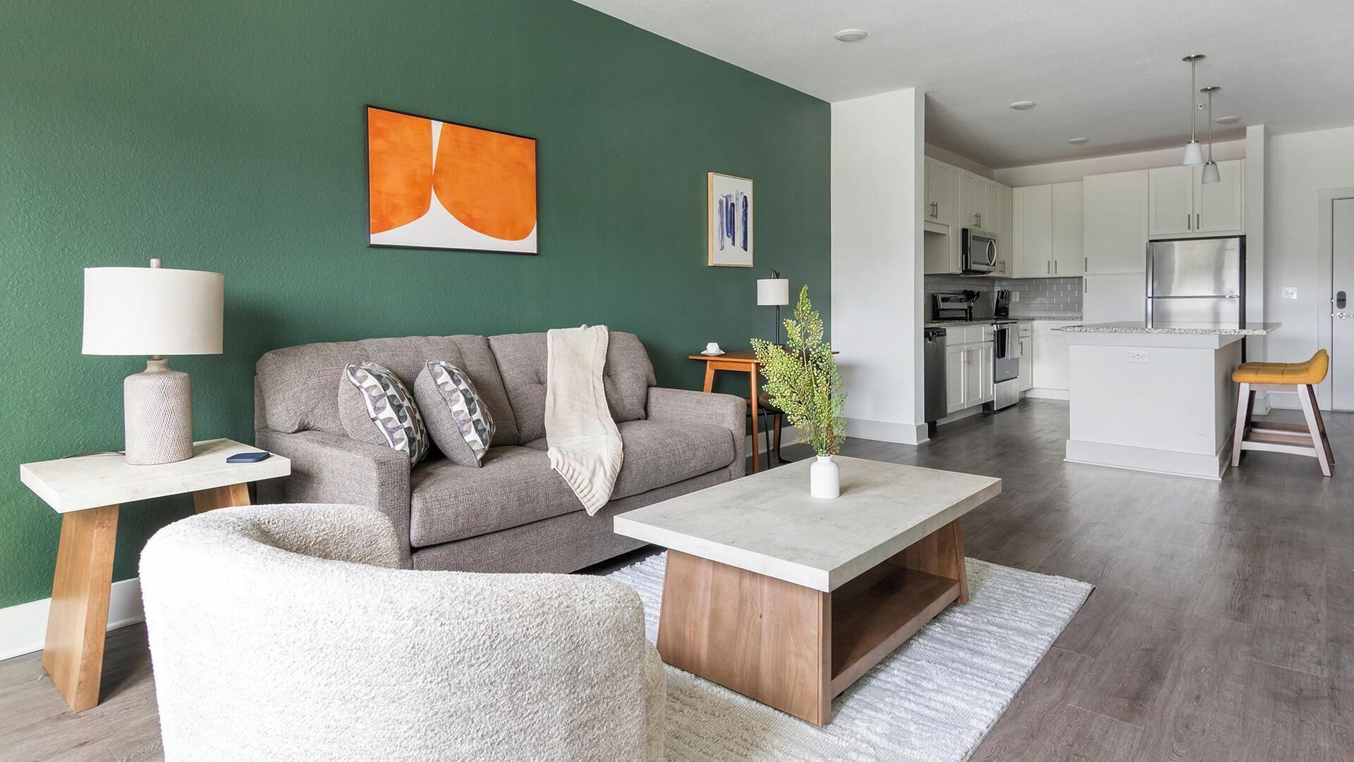 En moderne stue med en grå sofa, et sofabord og et lille vedhængsbord med en lampe.