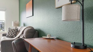 Una habitación con una mesa de madera, un sofá, una lámpara y un cuadro en la pared.