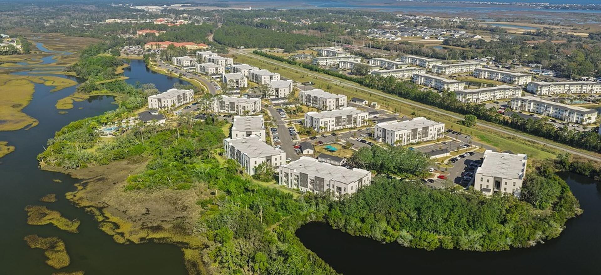 A residential area with modern buildings, a river, and a bridge.