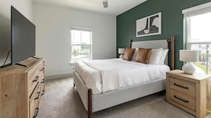 A bedroom with a bed, a TV, a dresser, and a nightstand. - Landing | Stylish 2BD, Gym (St. Augustine)