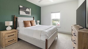 Une chambre à coucher avec un lit, des tables de chevet, une commode, un tableau et une fenêtre.