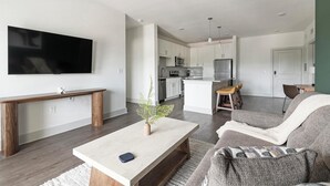 Un salon moderne avec un téléviseur à écran plat, une table basse, un banc et un canapé.