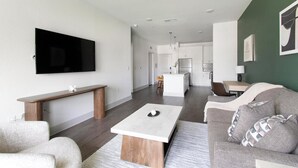 A modern living room with a flat-screen TV, a wooden coffee table, and a grey sofa. - Landing | Amazing 1BD, Gym (St. Augustine)