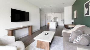 A modern living room with a flat-screen TV, a wooden coffee table, and a grey sofa. - Landing | Amazing 1BD, Gym (St. Augustine)
