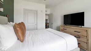 A hotel room with a bed, a television on a wooden dresser, and a door leading to another room. - Landing | Amazing 1BD, Gym (St. Augustine)