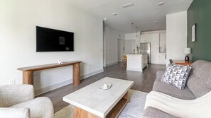 A modern living room with a flat-screen TV, a wooden coffee table, and a grey sofa with patterned cushions. - Landing | Stunning 1BD, Gym (St. Augustine)