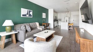 Ett modernt vardagsrum med en grå soffa, ett soffbord och en tv.