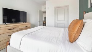 Ett hotellrum med en säng, en tv på en byrå i trä och en dörr som leder till badrummet.