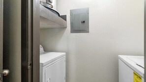 Ein Waschraum mit Waschmaschine, Trockner und einer Verteilungstafel an der Wand.