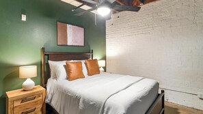 A bedroom with a bed, bedside tables, and a ceiling fan. - Landing | Stylish 1BD, Gym, Courtyard (Houston)