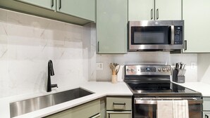 A modern kitchen with a stainless steel range, a microwave, and a sink. - Landing | Spectacular 1BD, Gym, Courtyard (Houston)