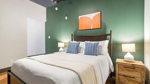 Ein Hotelzimmer mit einem Bett, zwei Nachttischen, einer Wandlampe und einem Bild.